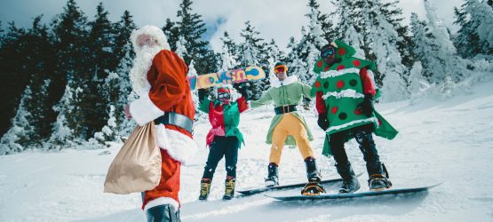 Santa Claus with elves ride snowboards