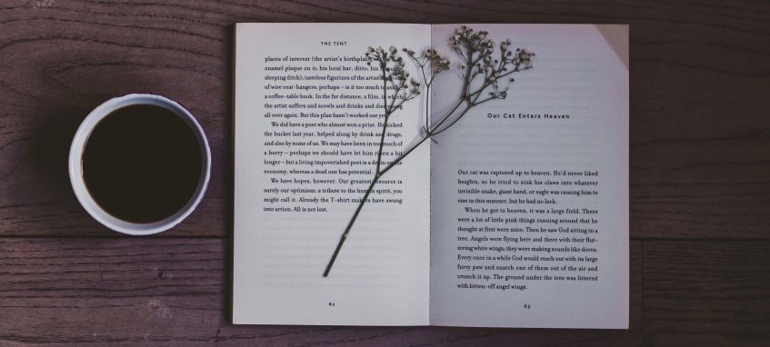 a book with a flower on it and a mug of coffee on a table