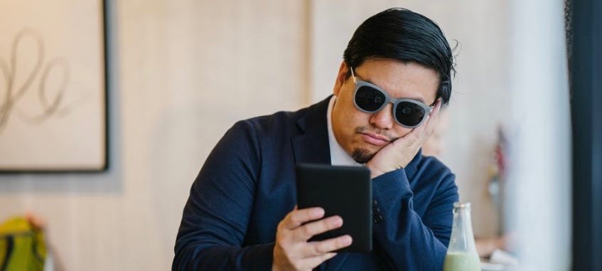 a bored guy in sunglasses making staring at phone screen