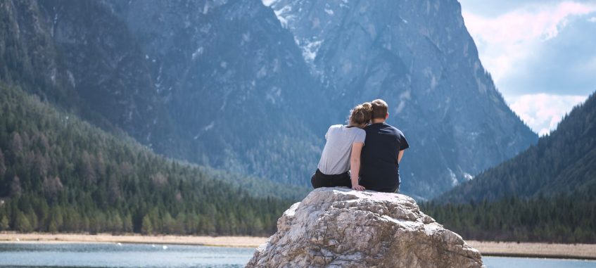 a college couple admiring mountain rocks at the lake