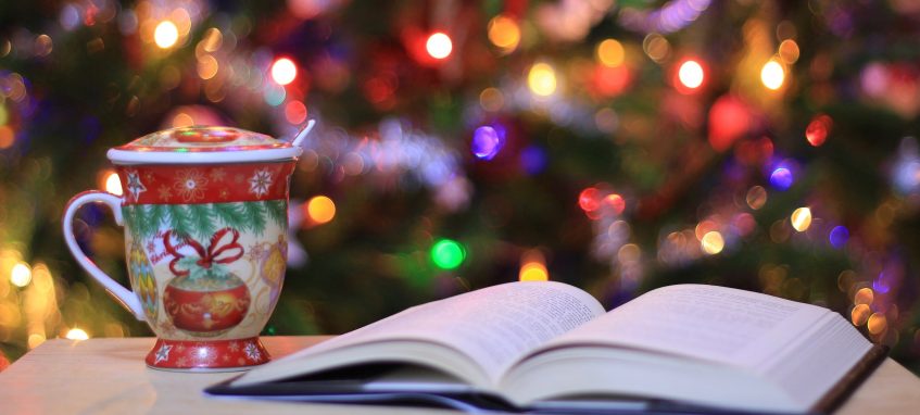 a decorated mug and a book with a christmas tree in the background