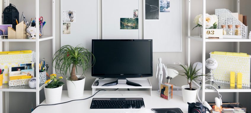 a desk with a computer on it and shelves with colorful stationery items