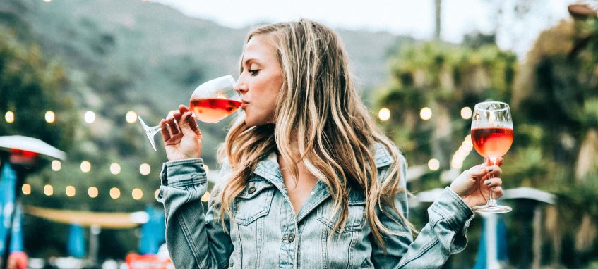 a girl drinking two glasses of wine simultaneously