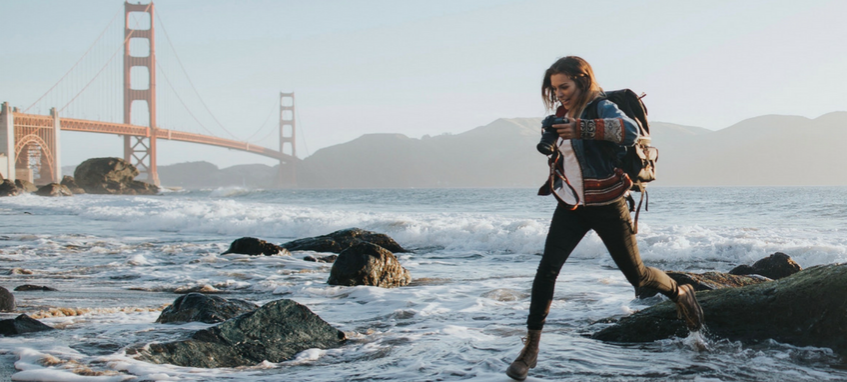 a girl jumping from stone to stone on the beach