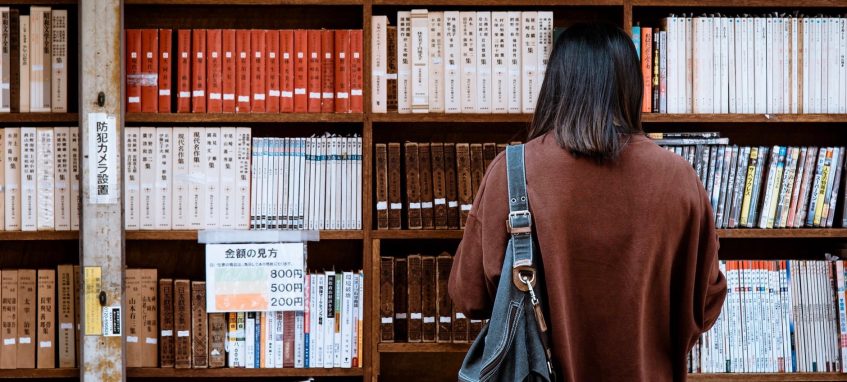 a girl looking at the shelves with books in a bookstore