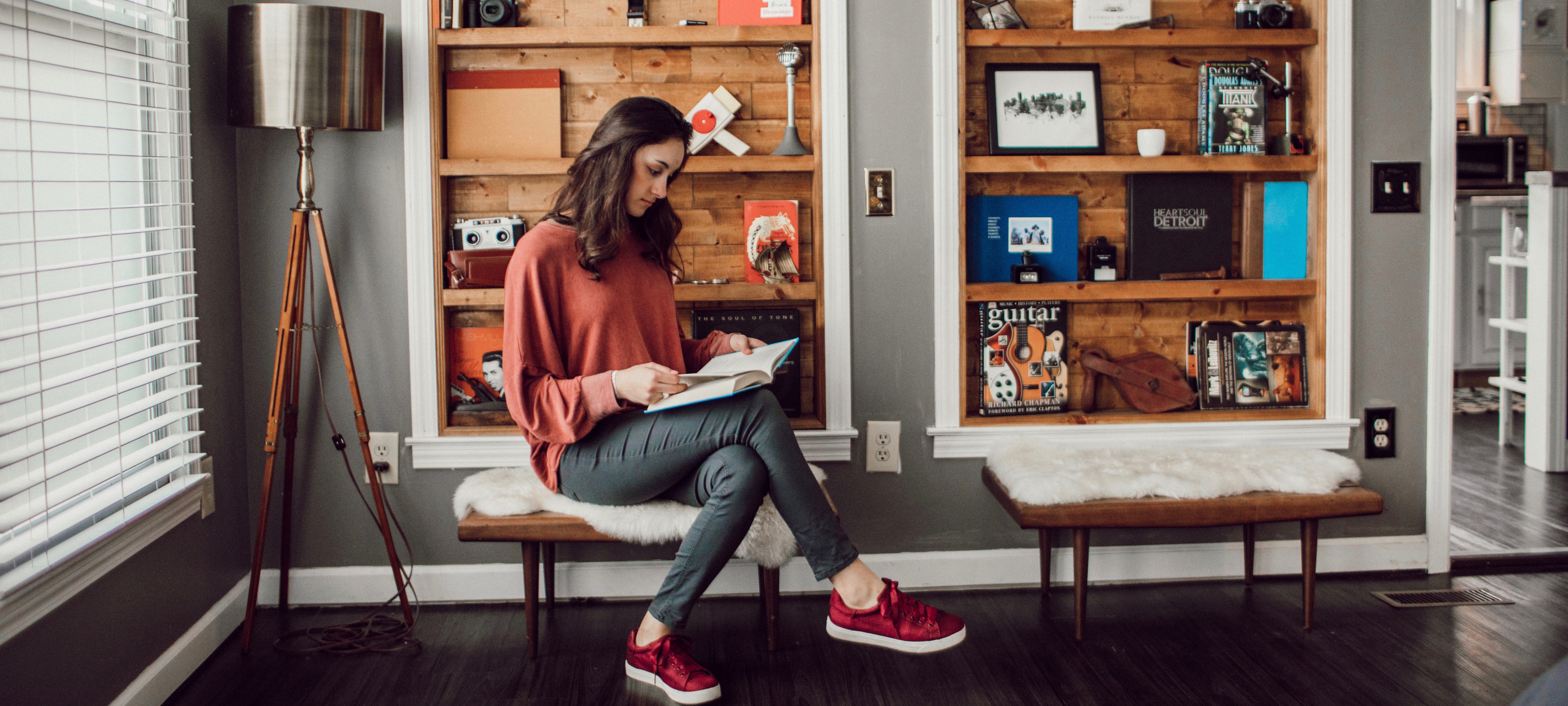 a girl reading a book in the room full of books