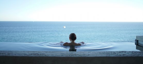 a girl swimming in the pool looking at the sea