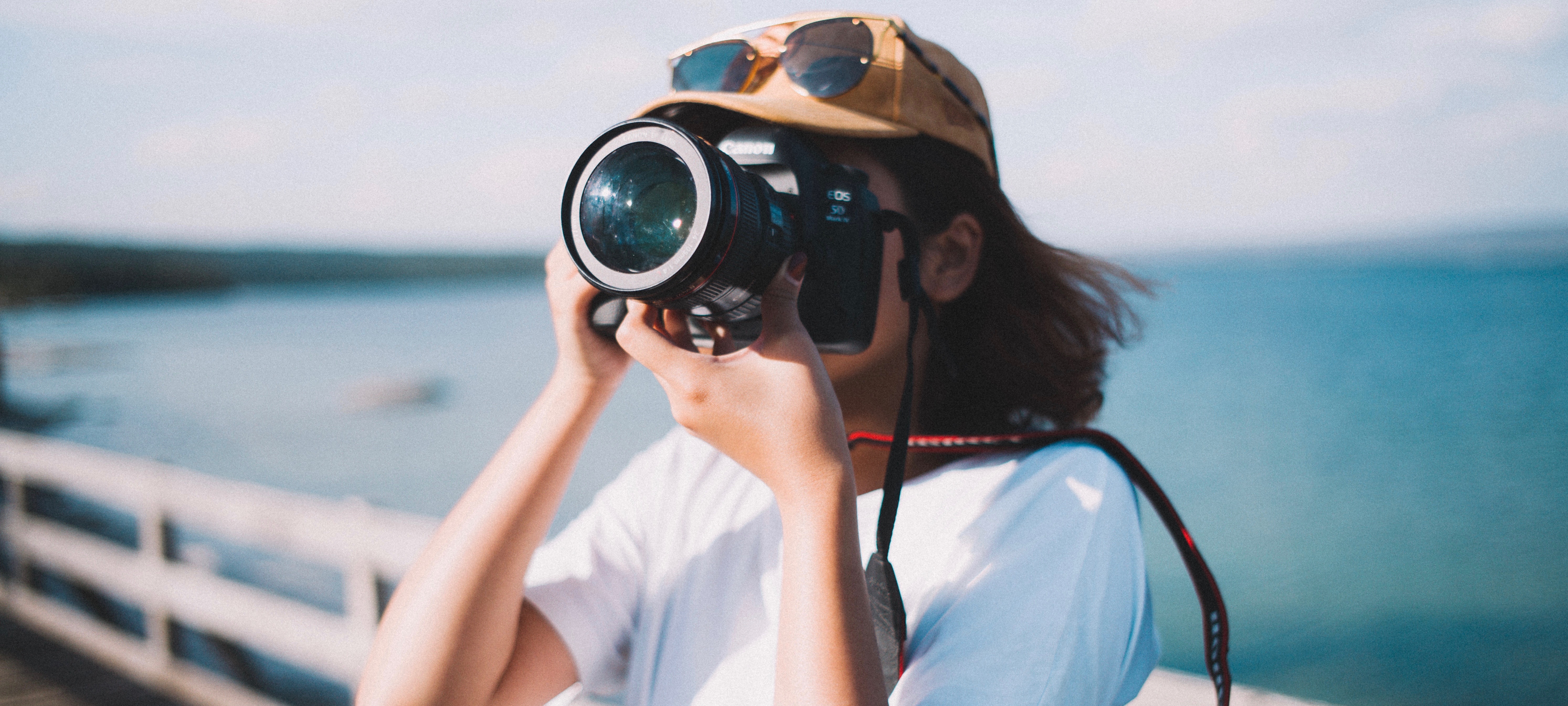 a girl taking photos in the background of the sea