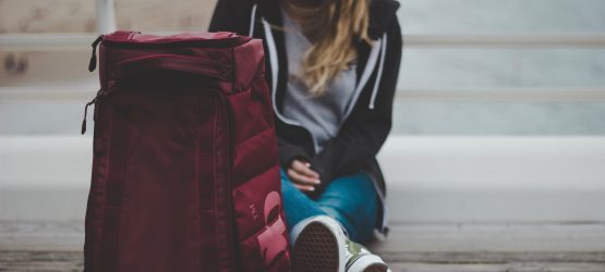 a girl with a backpack sitting on the ground