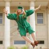 a graduate girl jumping up near the university