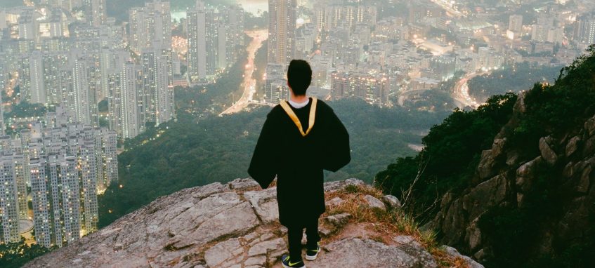 a graduate student stands on the hill looking at the city