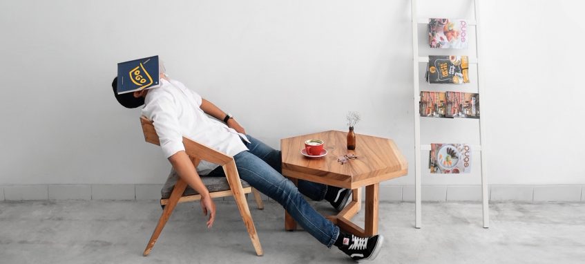 a guy sitting at the table with a book on his head