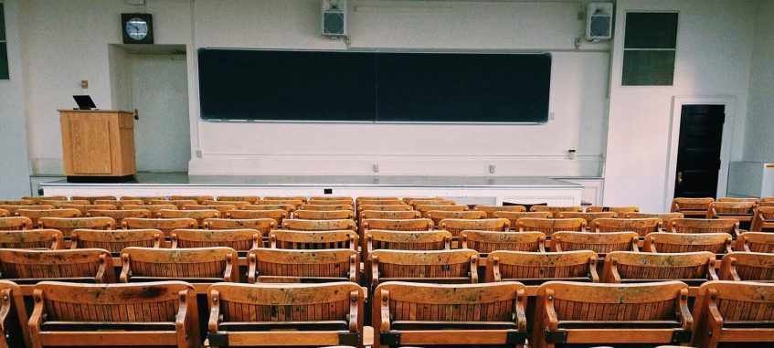 a lecture classroom with wooden seats