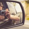a man taking photo of his reflection in the car mirror