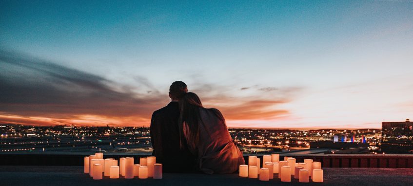 a young couple surrounded with candels looking at sunset