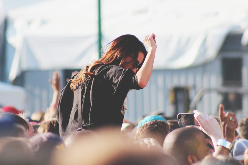 a young girl sitting on someone's shoulders at concert