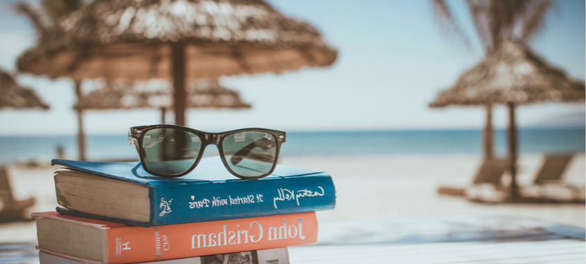 books and sunglasses the with the background of the beach