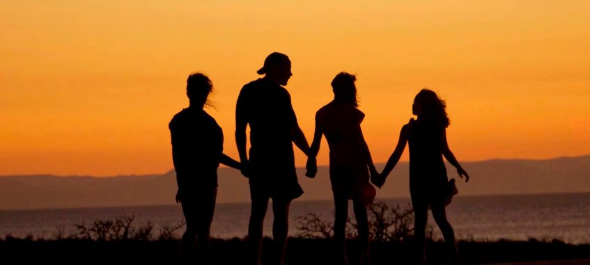 family members hold each others hands looking at the sea