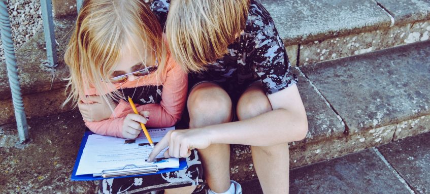 girl and boy doing homework on the porch