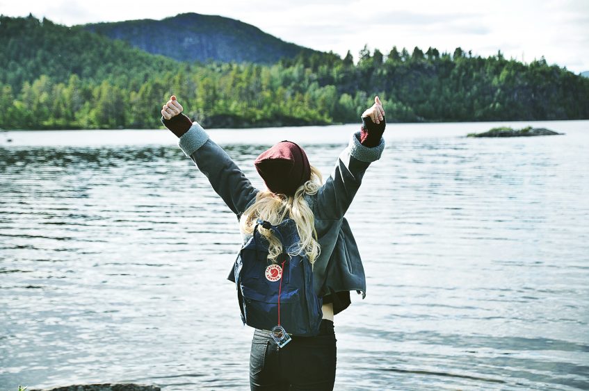 happy girl with hands up near the lake