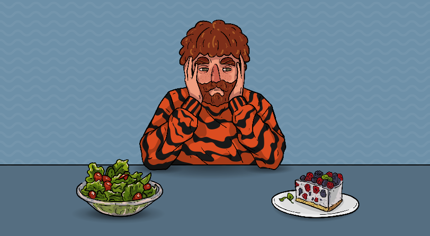 a guy in a tiger sweater is sitting next to a bowl of salad and a piece of cake