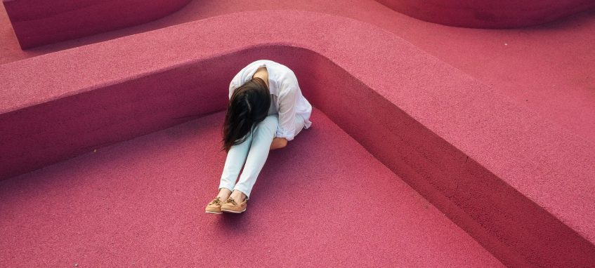 lonely girl sitting head to knees on the floor