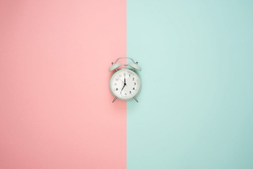 a clock on a pink and blue background