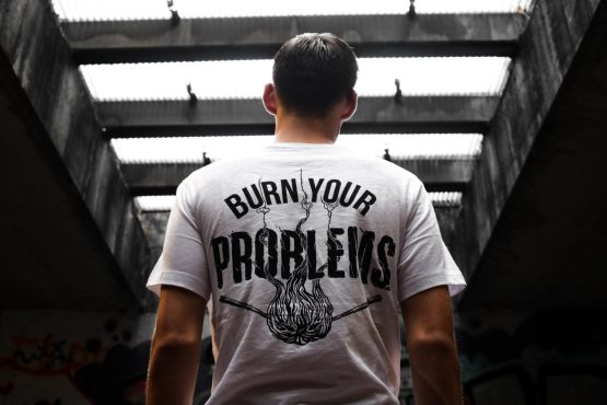 a guy wearing a t-shirt that says burn your problems