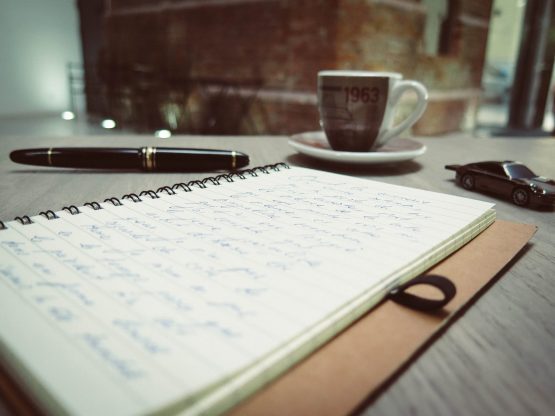 a notebook, a cup, and a pen on the table