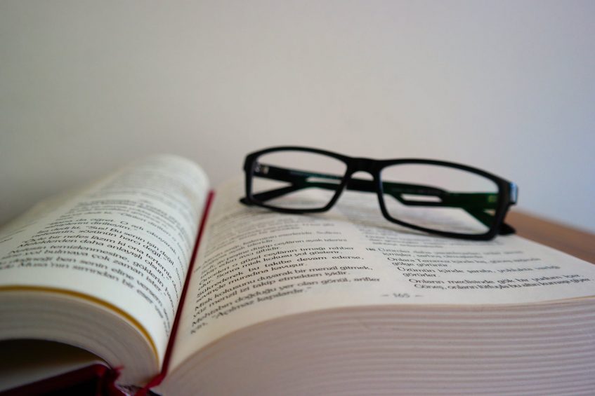 glasses lying on the opened book