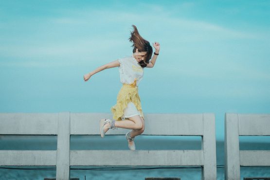 girl jumping next to a fence and a field