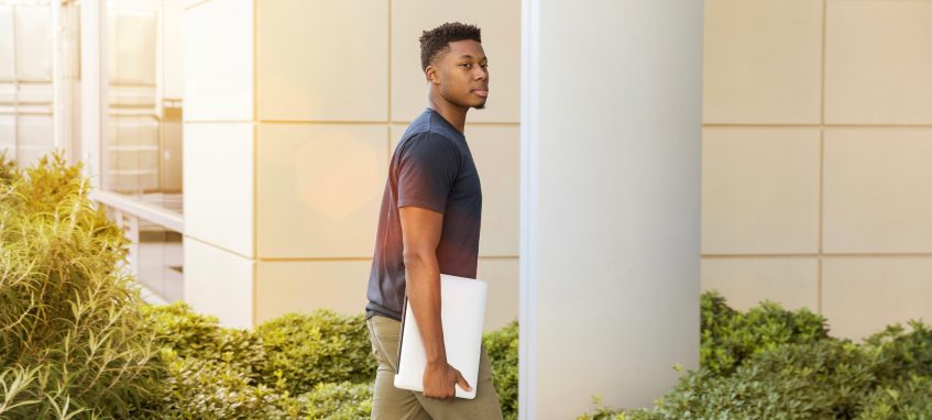 student with a paper in hand entering college building