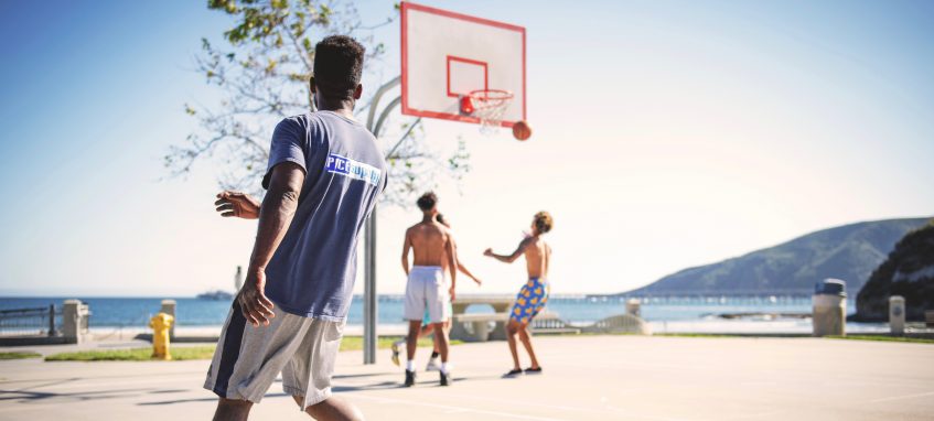 three guys play basketball outside