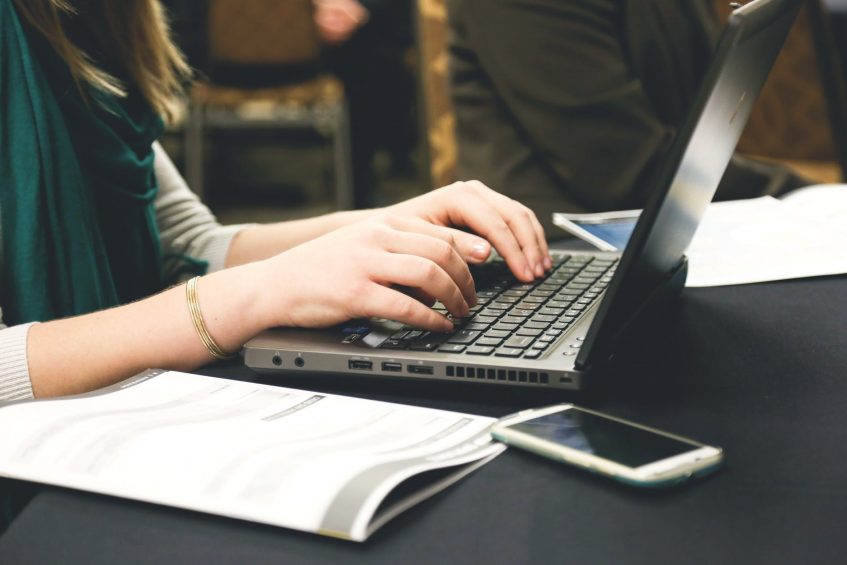 woman typing on laptop writing