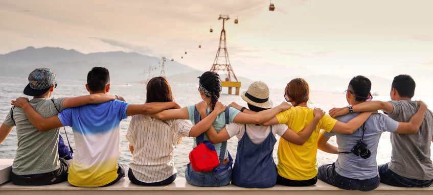 young people are hugging each other looking at the sunset